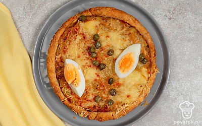 Украсьте горячий луковый пирог дольками куриных яиц и маринованными каперсами. 