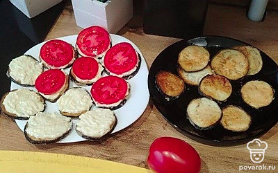 Намажьте соусом баклажаны. Помидор нарежьте кольцами и выложите сверху. 