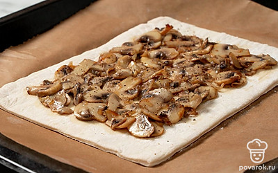 Выложите тесто на противень. Равномерно распределите на тесте грибную начинку, отступая от края теста на 3-4 см. 
