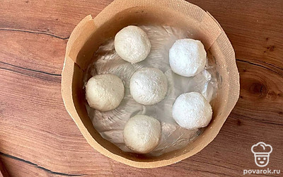 Форму диаметром 16-18 сантиметров смазать сливочным маслом и застелить бумагой для выпечки. Из творожной массы сформировать небольшие шарики, выложить их на дно формы.