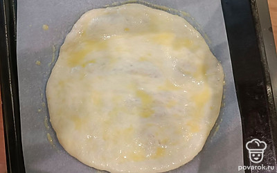 Взять духовочный лист, застелить его пергаментной бумагой. Затем ладошками немного растянуть фаршированную лепешку, приминая ее и расправляя начинку. Переложить на лист, смазать пирог яичным желтком и отправить в духовку на 30 минут при 200 градусах.