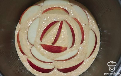 Нарежем яблоко. Тесто выльем в форму для выпечки, сверху положим нарезанные яблоки. Поставим в разогретую до 180 градусов духовку и будем выпекать пирог около 45 минут.