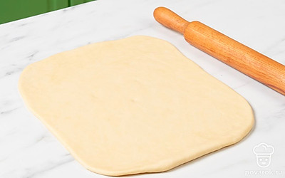 Смажьте поверхность стола и скалку растительным маслом. Достаньте тесто из холодильника и переложите его на стол. Немного прижмите его руками к столу и раскатайте в тонкий пласт прямоугольной формы. Толщина пласта должна быть около 2 мм.