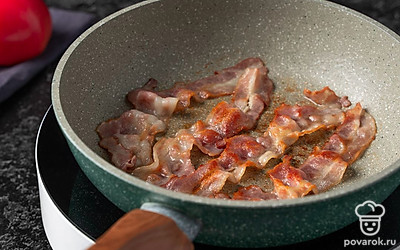 Разогрейте сухую сковороду на среднем огне. Обжарьте полоски бекона по 2-3 минуты с каждой стороны.