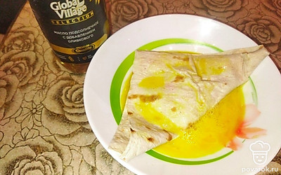 Сверните лаваш треугольником. Отправьте в тарелку со взбитым яйцом и обваляйте с двух сторон для обжарки на подсолнечном масле.