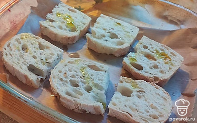 Выложите ломтики чиабатты на форму, застеленную пергаментом. Сбрызните ломтики оливковым маслом. Отправьте в духовку на 3 минуты. 