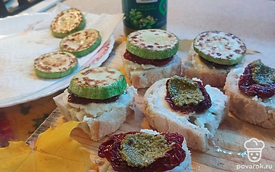 На вяленый помидор выложите по 0,5 чайной ложки соуса песто. Накройте ломтиком кабачка.