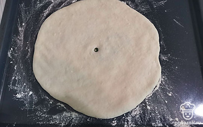 Пирог выложить на противень, посыпанный мукой. В центре сделать дырочку. 