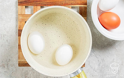 Выложите 2 яйца в кастрюлю и залейте холодной водой. Поставьте на средний огонь. После закипания варите 7-8 минут. Готовые яйца очистите и нарежьте кубиками.