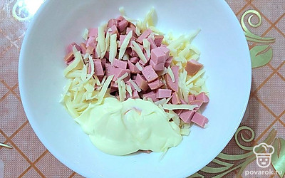 В отдельной посуде смешайте сыр, колбасу и майонез.