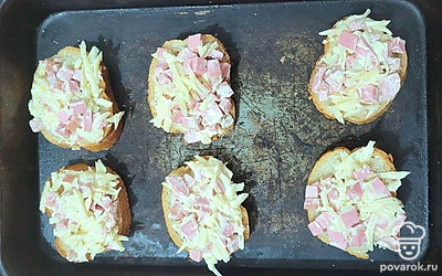 Батон нарежьте, нанесите на ломтики получившуюся колбасно-сырную смесь. Запекайте в духовке 10 минут при 180 градусах.