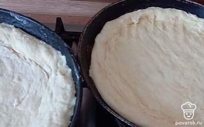 Когда тесто поднимется, делим его на 2 части и перекладываем на две небольшие сковородки. По краям формируем бортики, чтобы начинка не вылилась. 