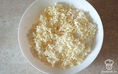 В сметану добавьте 50 грамм сахара, перемешайте и пока отставьте в сторону. В глубокую миску просейте муку, добавьте разрыхлитель и перемешайте. В муку натрите холодное сливочное масло на крупной терке.