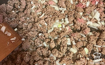 Добавляем лук к фаршу, перемешиваем, солим, перчим и обжариваем вместе до готовности фарша.