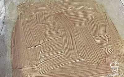 Раскатываем тесто и смазываем его соусом, отступая от края.