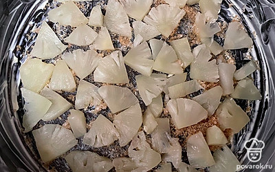 Смажьте столовой ложкой сливочного масла форму для пирога. Посыпьте двумя столовыми ложками тростникового сахара. Сверху выложите ананасы.