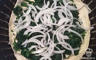 Когда тесто растаяло, распределить его на смазанную форму. Сверху положить шпинат, лук полукольцами. 