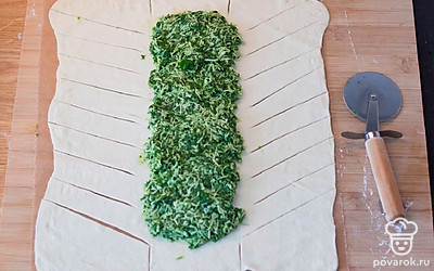 Выложите по центру начинку, не доходя краев. По бокам оставьте большое расстояние, сверху – по паре сантиметров. Ножом для пиццы сделайте надрезы: сверху и снизу сделайте по 2 разреза по ширине вашей начинки, боковые края нарежьте на полоски шириной 1,5-2 сантиметра под углом, «елочкой».