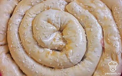 «Колбаски» укладываем в форму в виде улитки, смазываем яйцом и посыпаем кунжутом. Ставим в разогретую до 180 градусов духовку примерно на 40 минут.