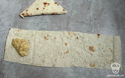 Лаваш разрежьте на полоски. Положите на каждую по 1 столовой ложке банана и сверните в треугольник.