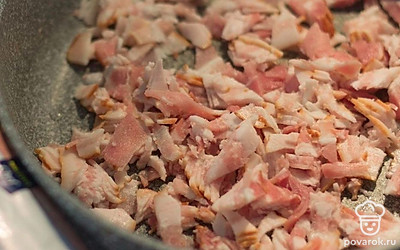 Порежьте бекон и обжарьте его на сухой сковороде. По желанию на этом этапе добавьте зубчик чеснока.