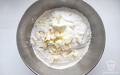В просеянную муку добавьте сметану и размягченное сливочное масло, порезанное на кубики. Замесите тесто, оно должно получиться эластичным и податливым, оберните его пищевой пленкой и уберите на 15 минут в холодильник.