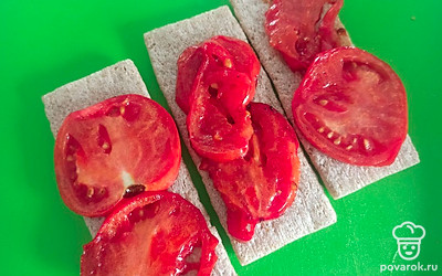 Выложите на хлебцы обжаренные дольки помидора.