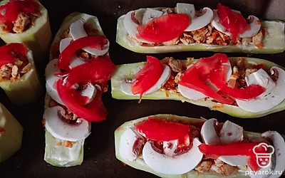 Очищенные половинки кабачка посолите, поперчите. Положите внутрь фарш, сверху разложите кусочки шампиньонов и помидора. Отправьте в духовку минут на 30 при температуре 170 градусов. 