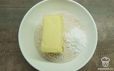 Перетрите в миске муку с содой и маслом, влейте лимонный сок и замесите тесто. Около ¼ части теста положите в морозильную камеру, а остальное распределите в форме, сформировав дно и бортики будущего пирога.