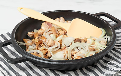 Приготовьте начинку для пирога. Раскалите на сковороде масло, выложите лук и обжарьте его до прозрачности. Затем выложите шампиньоны и жарьте еще 7 минут, пока не выпарится влага. Добавьте филе и жарьте 6 минут, часто помешивая, пока оно не посветлеет. Немного приправьте начинку солью и уберите со сковороды.