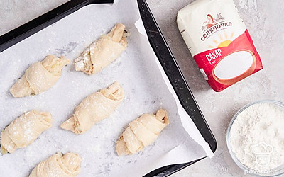 Приготовьте пирог. Подготовленное тесто разделите на 3 равные части. Каждую часть раскатайте в небольшой пласт и смажьте луковой начинкой. Далее наложите пласты друг на друга и разрежьте их на 16 равных треугольников. Каждый треугольник закрутите в рогалик, а затем выложите в форму для выпекания. Оставьте заготовки на 30 минут, а после поместите в духовку до полной готовности при температуре 180 градусов.