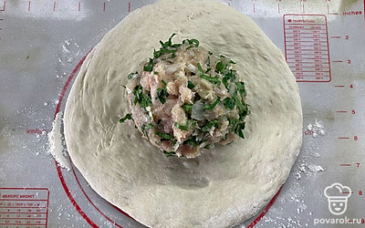 Тесто размять руками в круг. Из начинки скатать шар и поместить в центр круга. 