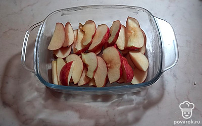 Выложите яблочные дольки на дно формы для выпечки.