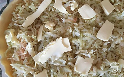 Тесто разделите на 2 части. Раскатайте первую часть теста как толстый блинчик диаметром чуть больше формы. Выложите начинку, сверху на начинку можно положить кусочки сливочного масла.