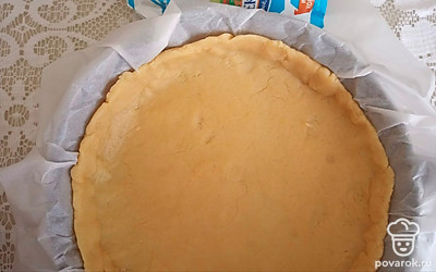 Первый кусок теста раскатайте на бумаге для выпечки и уложите на дно формы.