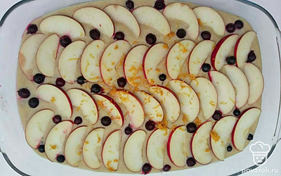 Форму для запекания смажьте сливочным маслом, вылейте тесто. Яблоки вымойте, очистите от сердцевины и нарежьте тонкими ломтиками. Натрите на мелкой терке цедру лимона. Сверху на тесто выложить яблоки и черноплодную рябину, посыпьте лимонной цедрой. Отправьте форму в разогретую духовку до 180°C на 45 минут.