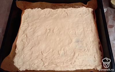 На противень положите антипригарный коврик, потом выложите на него тесто и растяните его руками до краев противня.