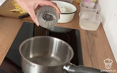 Займитесь начинкой. В кастрюлю налейте половину стаканы воды, добавьте оставшийся сахар и дождитесь, когда закипит, перемешивая.