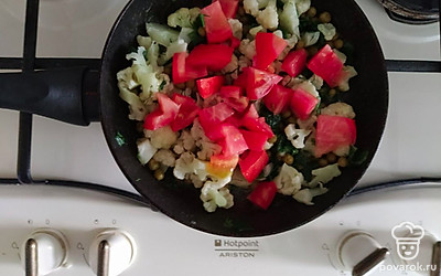 Обжарьте помидоры, цветную капусту и горошек. Посолите и добавьте порубленную зелень.