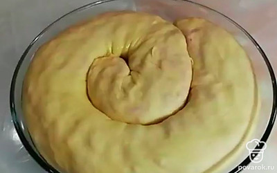 Достаньте тесто. Тонко раскатайте примерно в форму прямоугольника. Выложите начинку по всей площади, оставляя края по 3 см. Закатайте начиненное сверху тесто в колбаску и уложите в глубокую миску в виде улитки. Сверху намажьте сливочным маслом, накройте фольгой. Сделайте вилкой проколы и выпекайте в духовке 40 минут при температуре 200°C.