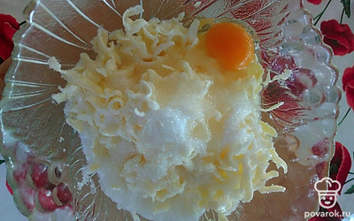 Сливочное масло натрите на терке, добавьте сахар, яйцо и муку с разрыхлителем. Замесите песочное тесто и распределите его по форме.