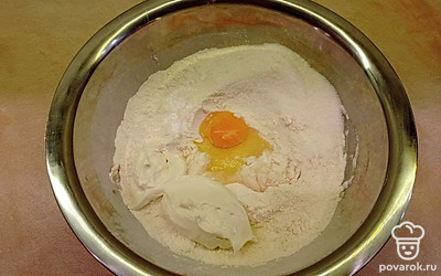 В глубокой миске смешайте просеянную муку с сахаром и разрыхлителем. Затем вбейте в миску яйцо, добавьте сметану. Охлажденное сливочное масло порубите ножом и добавьте к муке и другим ингредиентам. Руками вымесите тесто до однородного состояния.
