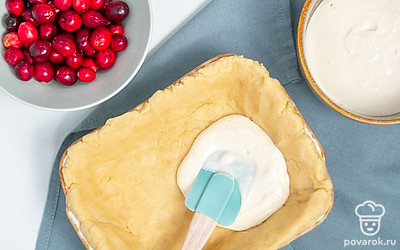 Приготовьте пирог. Отдельно смешайте сметану, сахар, куриное яйцо, ванилин и крахмал. Сверху на тесто равномерно выложите клюкву и вылейте сметанную заливку. Поставьте форму в духовку на 40 минут. После чего дайте десерту остыть и переложите на тарелку.