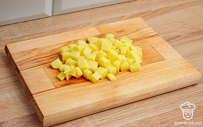 На разделочной доске кубиками нарежьте картофель.