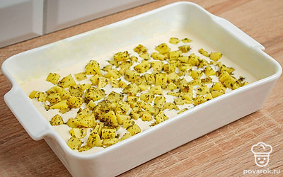 Возьмите форму для запекания и смажьте ее дно сливочным маслом. Залейте в форму небольшой объем теста на муке, сметане и майонезе. Выложите в форму кубики картофеля в специях.