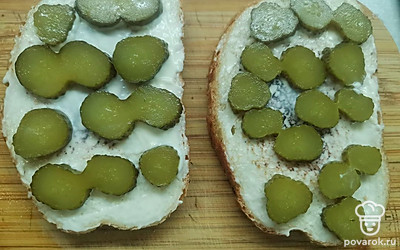 И смажьте тонким слоем майонеза. Выложите кружочки соленого огурца. 