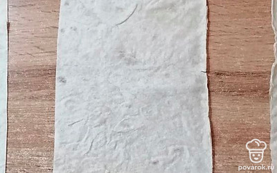 На каждую полоску лаваша выложите сосиску и сырную стружку.