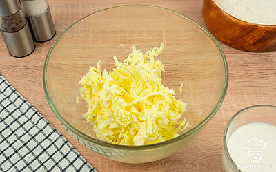 Приготовьте песочное тесто. Для этого подмороженное сливочное масло натрите на крупной терке. Переложите масло в глубокую миску.