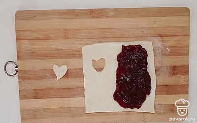 Вырежьте ножом или выдавите с помощью кулинарной формы отверстие в одной части квадрата из теста, а на другую часть выложите 1-2 ст.л. смородинового джема.