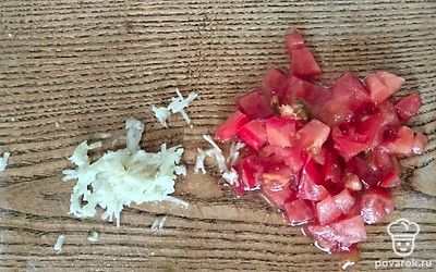 Нарежьте мелко помидор. Пропустите через пресс чеснок.